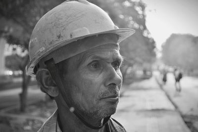 Close-up of senior man wearing hardhat standing outdoors