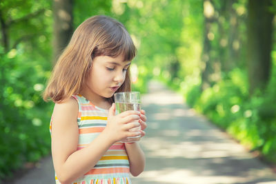 Cute girl drinking water while standing outdoors