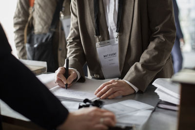 Midsection of businesswoman registering at counter during seminar