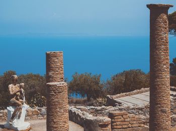 Close-up of old ruins against sea and clear blue sky