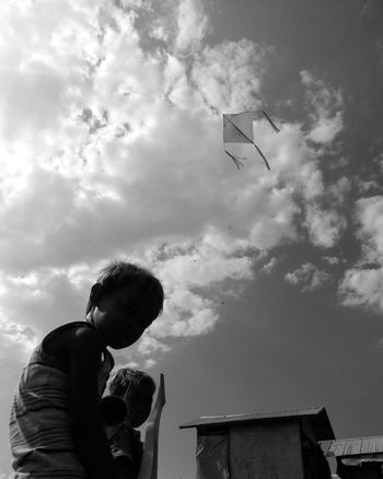 LOW ANGLE VIEW OF BOY STANDING BY SKY
