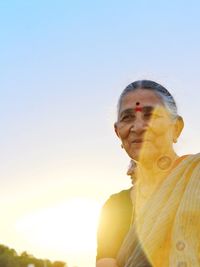 Woman looking away against clear sky during sunset