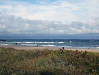 View of calm beach against cloudy sky