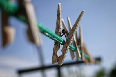 Close-up of clothespins on metal against blue sky