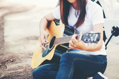 Midsection of woman playing guitar at beach