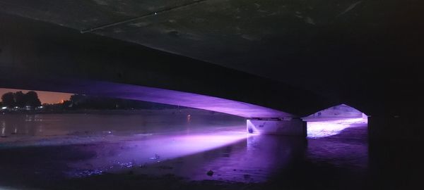 Illuminated bridge over river against sky at night