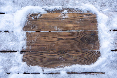 Close-up of snow on wooden plank during winter