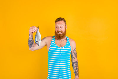 Man standing against yellow background