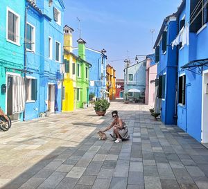 Woman with cat crouching on road in city