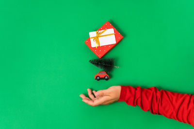 Cropped hand of woman holding gift against blue background