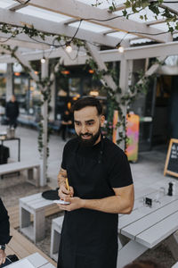 Smiling young male waiter taking food order at restaurant