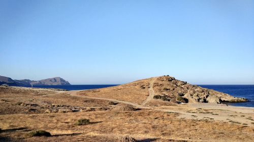 Scenic view of sea and mountains against clear blue sky