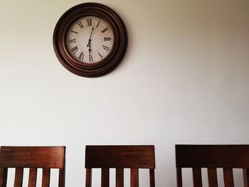 Low angle view of clock on table against wall