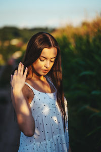 Young woman looking away while standing against plants