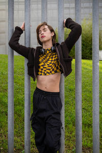 Portrait of young woman standing against fence