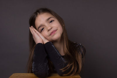 Portrait of smiling young woman sitting against black background