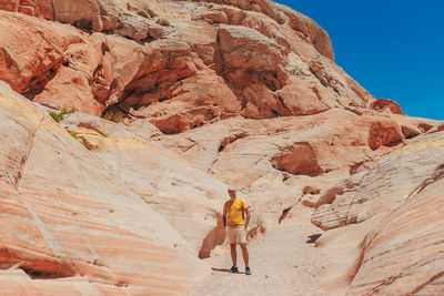Rear view of man walking on rock formations