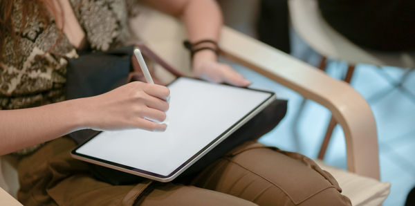 Midsection of woman using digital tablet