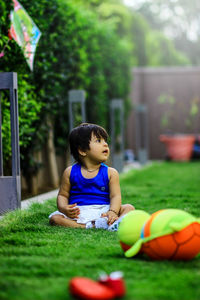 Cute girl with toys sitting on field at yard