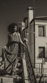 Portrait of smiling young woman standing against built structure