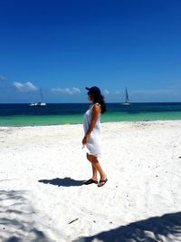 Rear view of woman standing on beach against clear sky