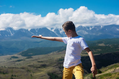 Rear view of man standing on mountain against sky