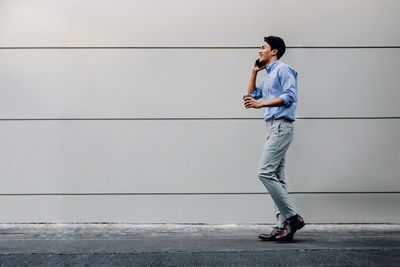 Side view of young man standing against wall