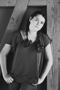 Portrait of teenage girl leaning on wooden wall