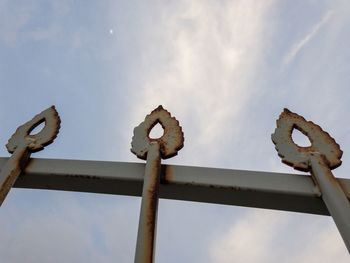 Low angle view of rusty metal railing against sky
