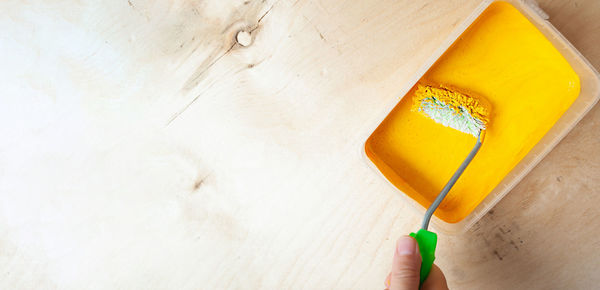 Close-up of hand holding yellow wall