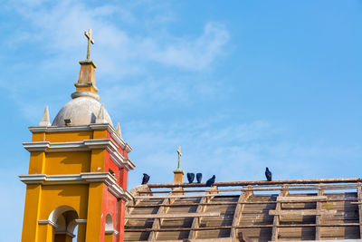 Low angle view of birds perching on church against sky