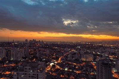 Illuminated buildings in city against sky at sunset