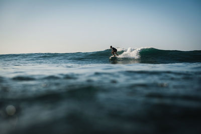 Man surfing on sea against clear sky