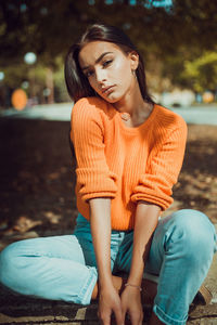 Young woman looking away while sitting on bench