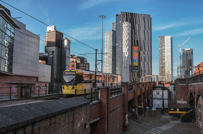 Road by buildings against sky in city