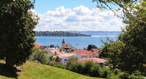 Houses by sea and buildings against sky