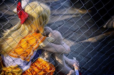 Girl sitting by chainlink fence