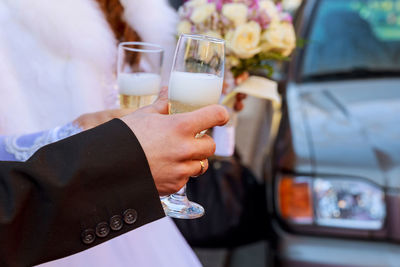Cropped hand of bride and groom holding champagne flutes