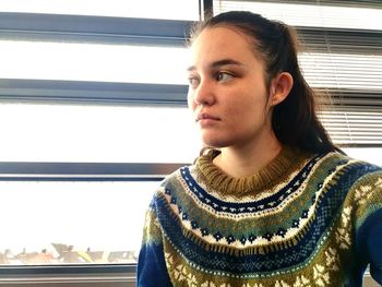 Young woman standing against window