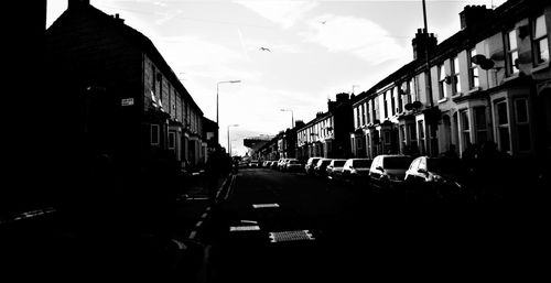 Cars on street amidst buildings in city against sky