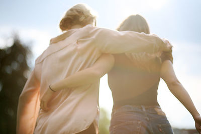 Rear view of women walking arm around outdoors