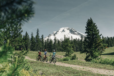 Three female friends mountain bike on a trail at mt. hood, oregon.