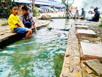 Rear view of people sitting in canal