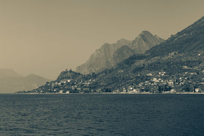 Scenic view of sea by mountains against clear sky