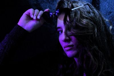 Portrait of senior woman holding camera against black background