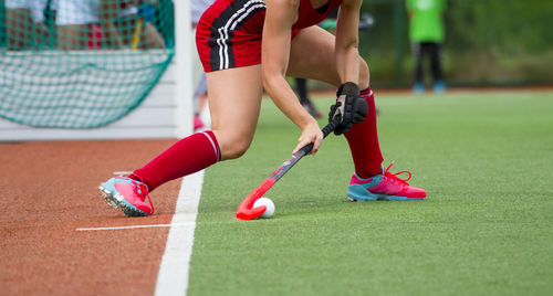 Low section of woman playing hockey in court