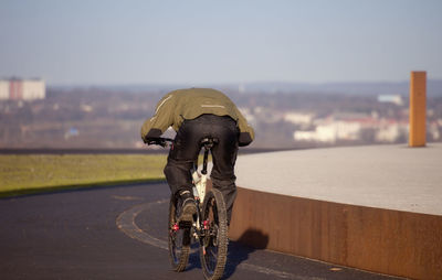 Rear view of man riding bicycle on road