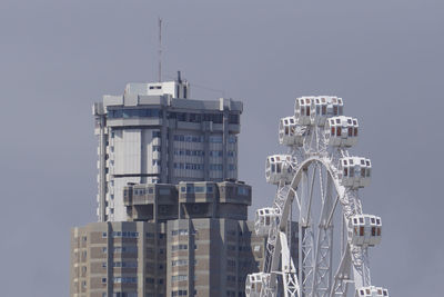 Wheel and buildings in city against clear sky