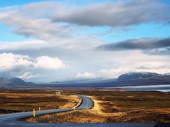 Road passing through landscape against cloudy sky