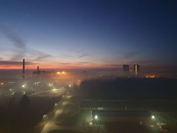 Aerial view of illuminated city against sky during sunset